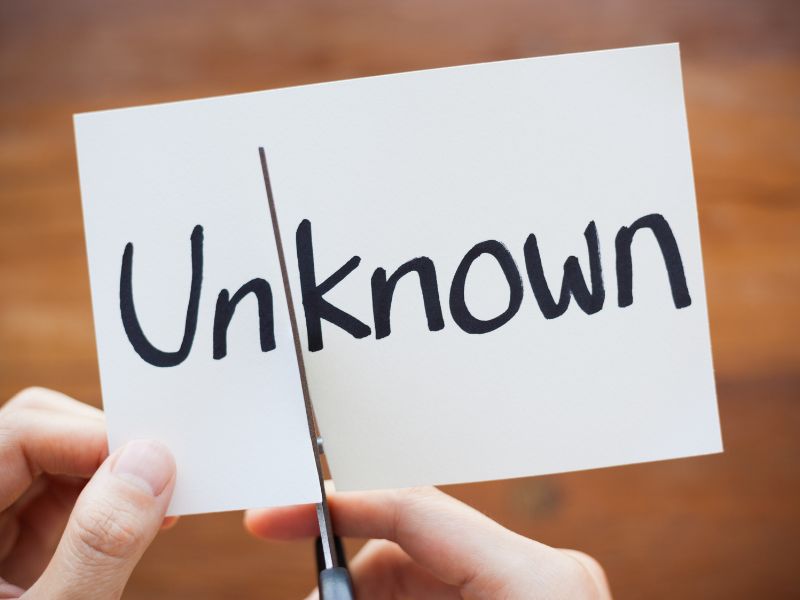 A person cutting the word unknown into just known